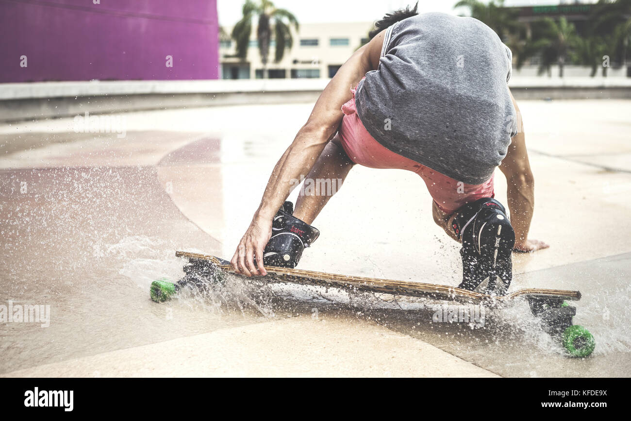Ein Skateboarder unten hocken auf einem Skateboard durch Wasser. Stockfoto
