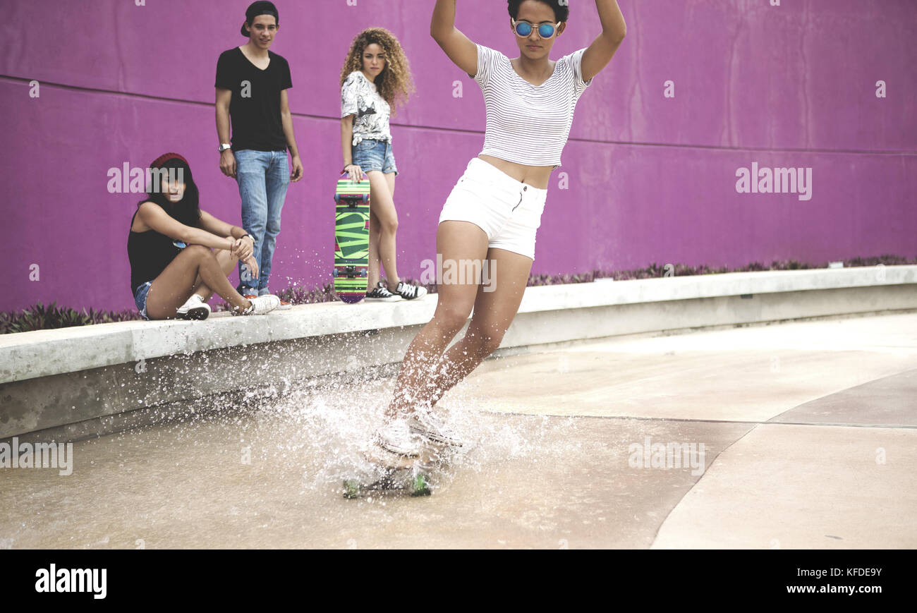 Eine junge Frau auf einem Skateboard durch Wasser. Stockfoto