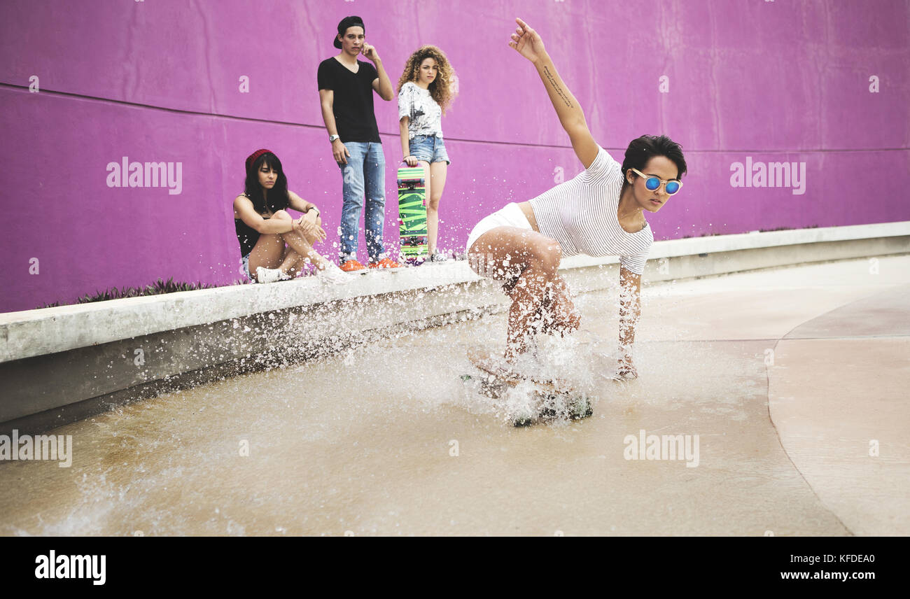 Eine junge Frau, kauern, einem Skateboard durch Wasser. Stockfoto