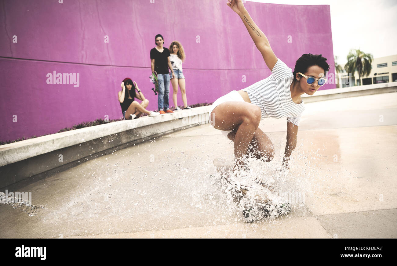 Eine junge Frau, die Hocken auf einem Skateboard eine Spritzwasser zu erstellen. Stockfoto