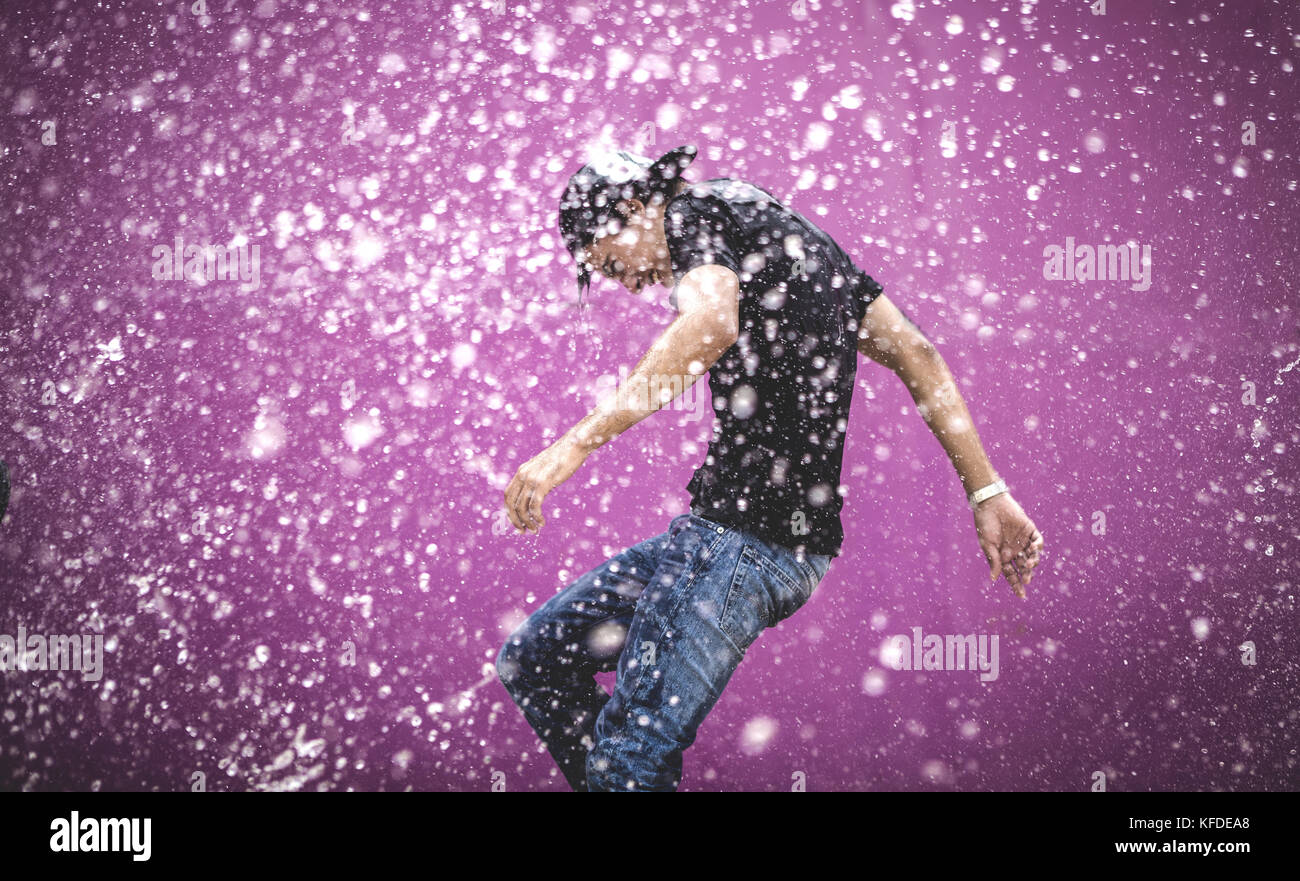 Junge Mann in einem Dusche von Wassertropfen. Stockfoto