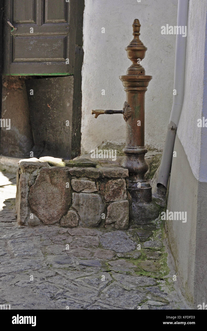 Eine alte Wasserpumpe in einer schattigen Ecke eines traditionellen Stadt an einem heißen Tag. Eine geheimnisvolle Tür im Hintergrund. Stockfoto