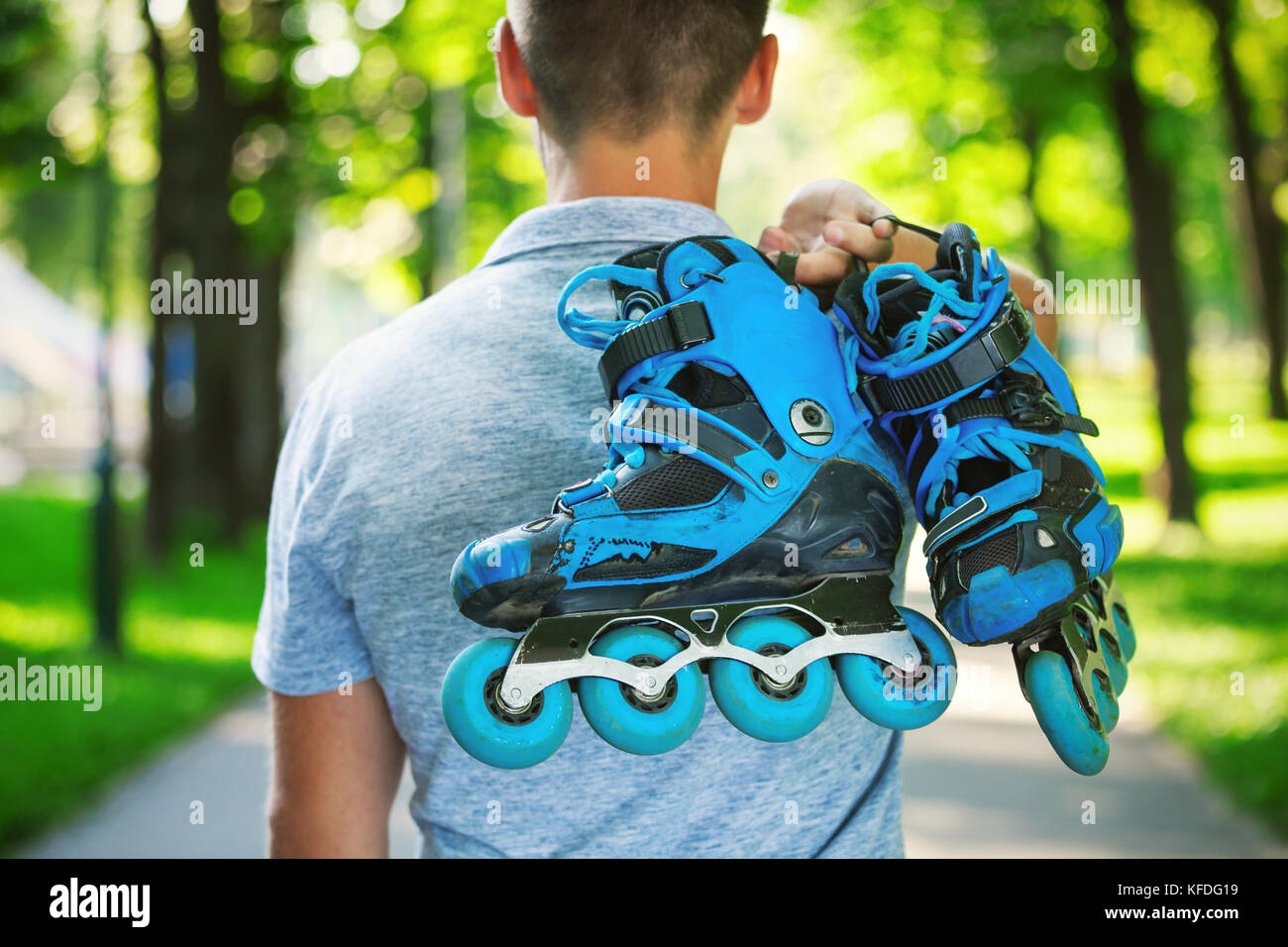 Junge männliche roller Skater holding Inline Skates. Von hinten Schießen. Stockfoto