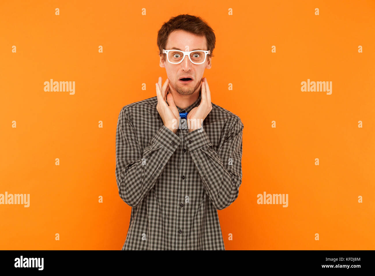 Crazy Student an der Kamera mit entsetzten Gesicht. Indoor, orange Hintergrund Stockfoto