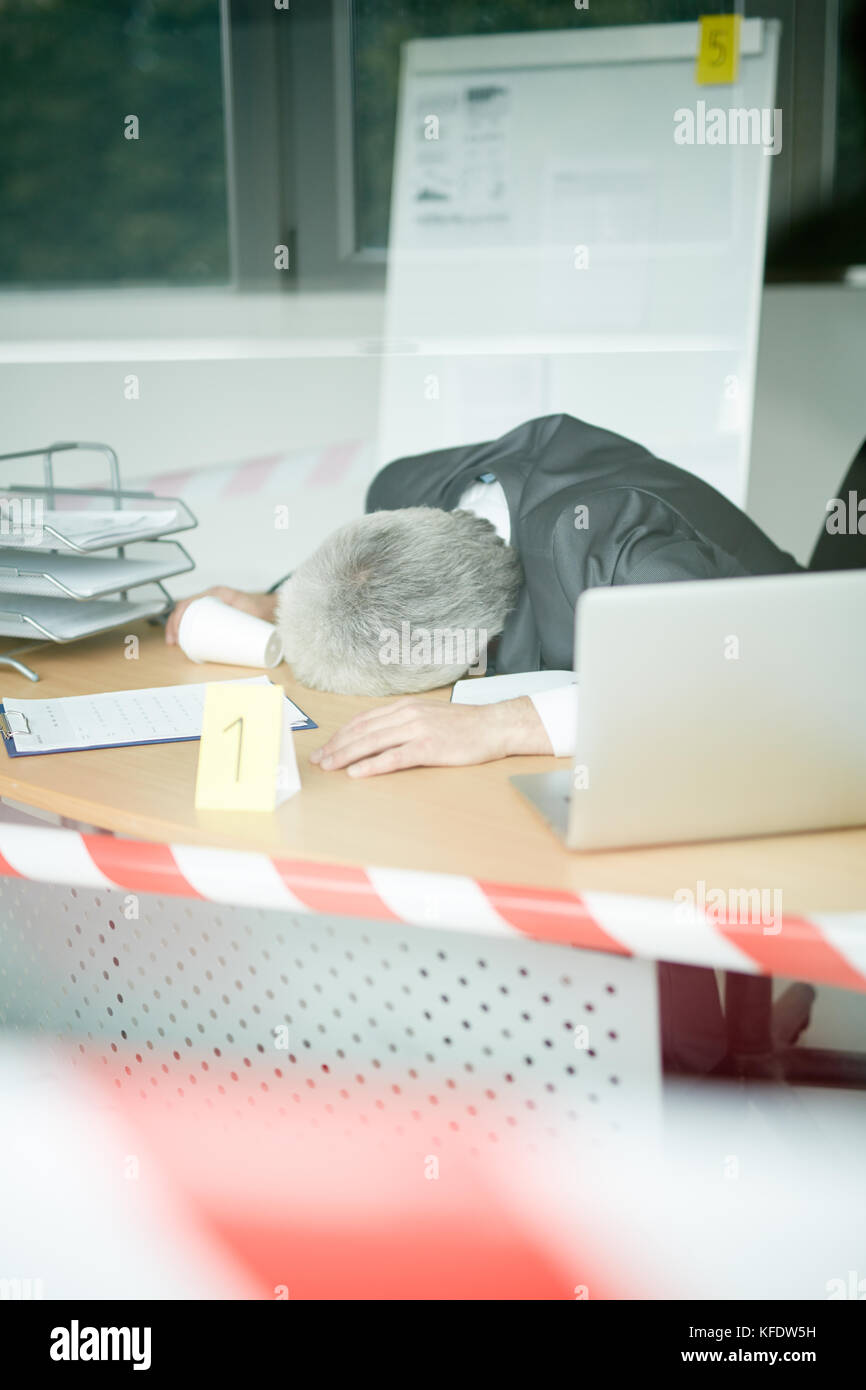 Tatort durch Panoramafenster: leblos älterer Geschäftsmann im klassischen Anzug liegen auf Büro Schreibtisch, gestreifte Tatort tape Stockfoto