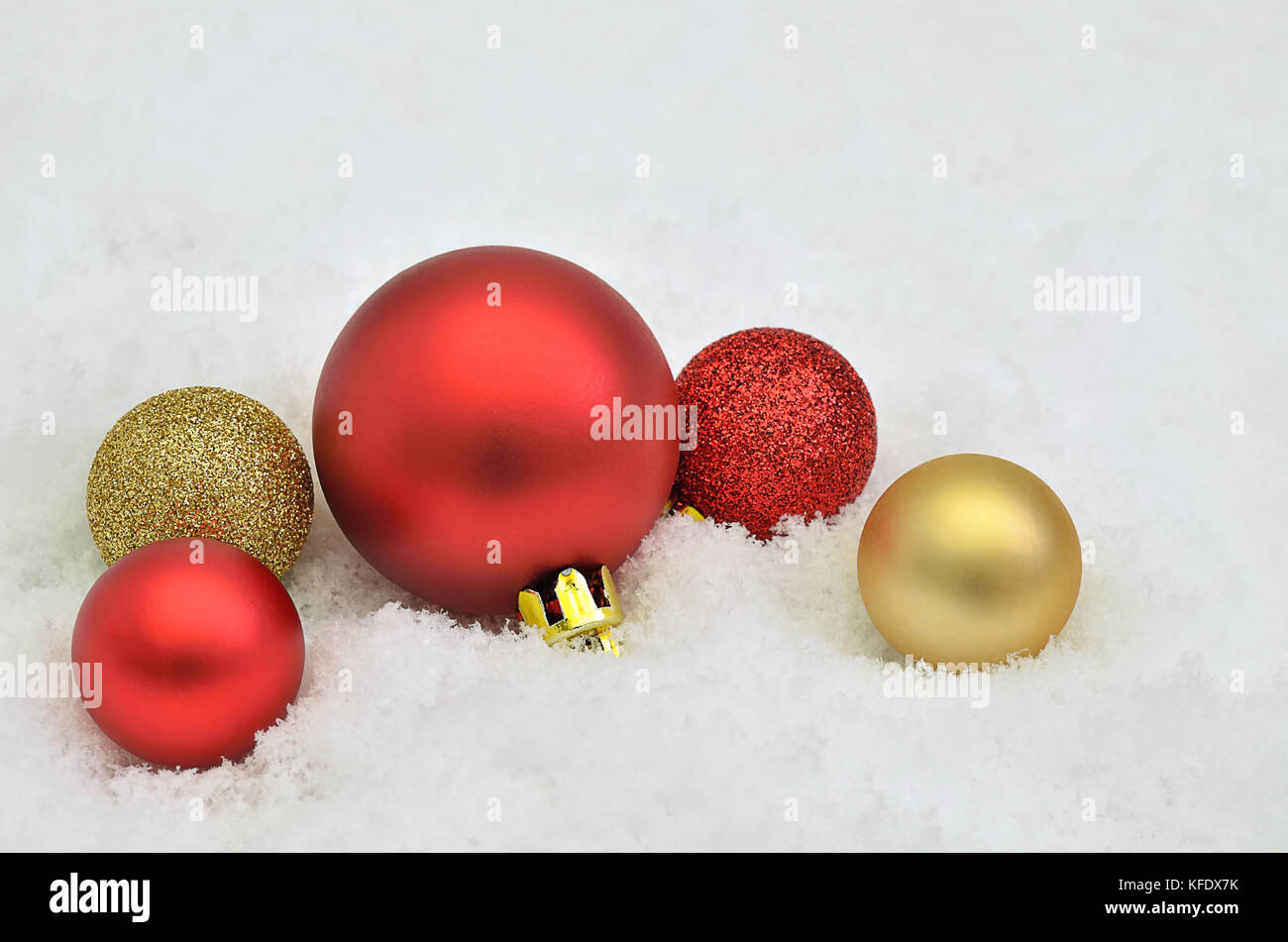 Nahaufnahme von roten und goldenen Weihnachtsbaum Kugel Ornamente auf Schnee Hintergrund Stockfoto