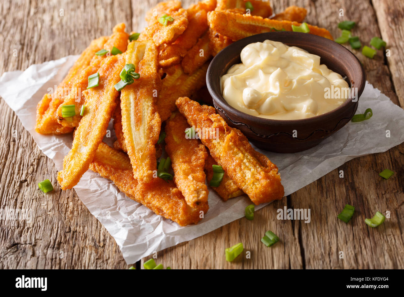 Gebratene baby Mais mit Frühlingszwiebeln und cremige Soße close-up auf einem Tisch. Horizontale Stockfoto