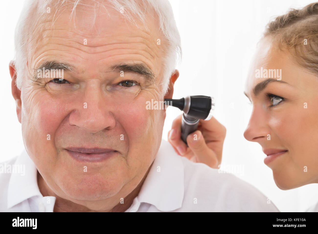 In der Nähe der weiblichen der Arzt, der die Untersuchung des Patienten Ohr mit otoskop Stockfoto In der Nähe der weiblichen der Arzt, der die Untersuchung des Patienten Ohr mit otoskop Stockfoto