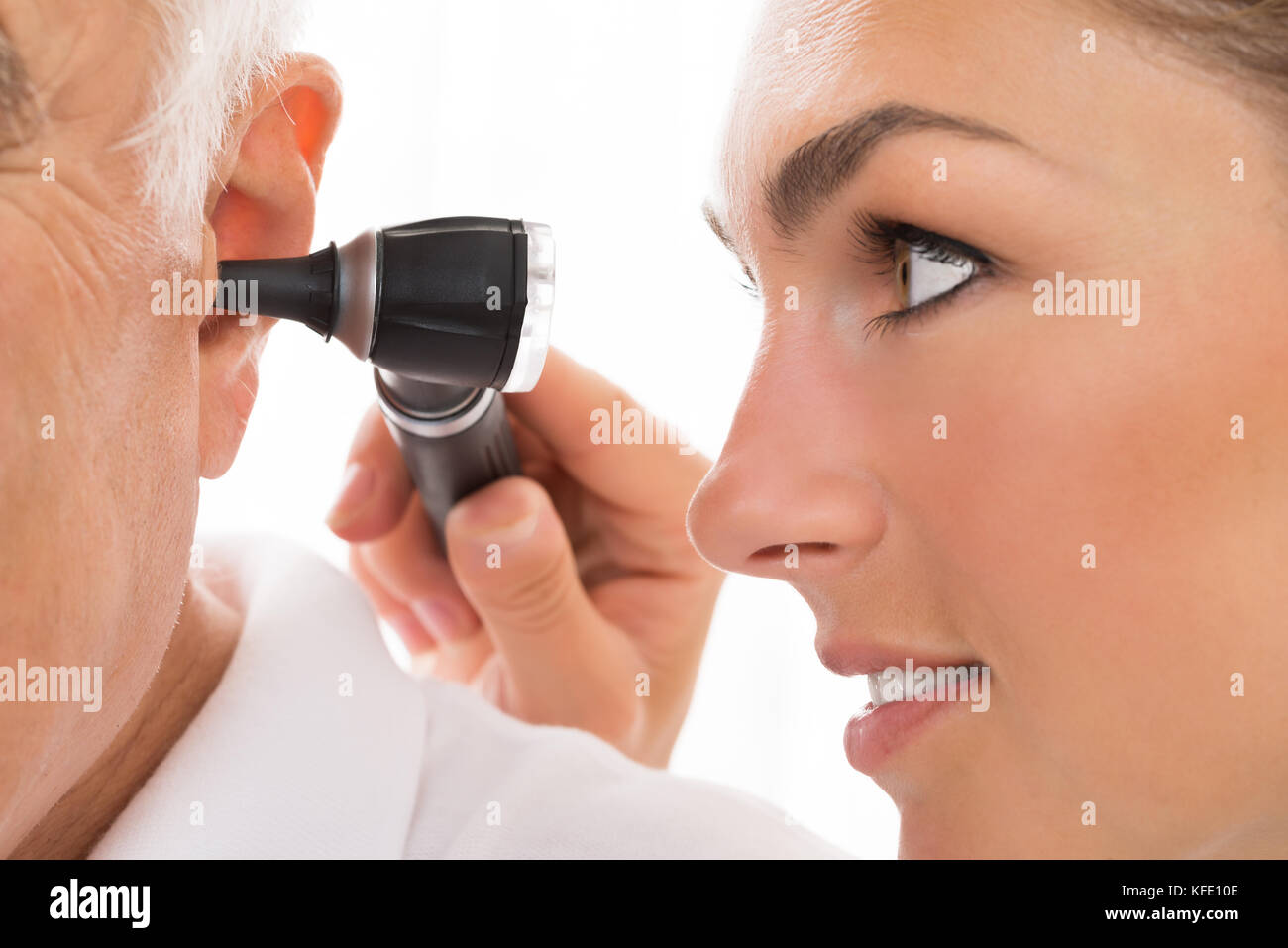 In der Nähe der weiblichen der Arzt, der die Untersuchung des Patienten Ohr mit otoskop Stockfoto In der Nähe der weiblichen der Arzt, der die Untersuchung des Patienten Ohr mit otoskop Stockfoto