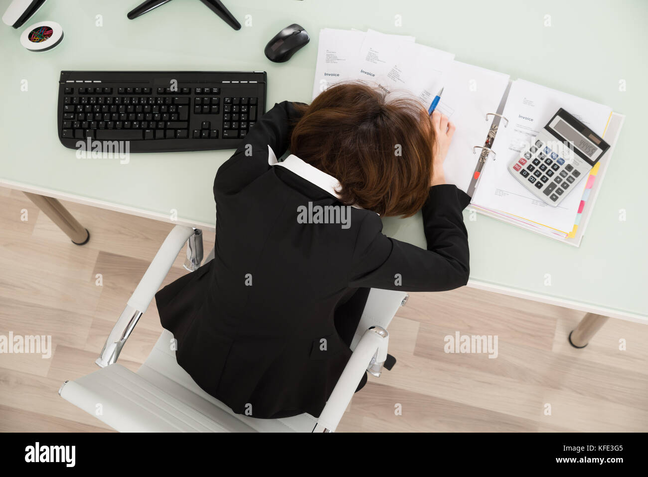 Junge Geschäftsfrau schlafen mit Rechnungen auf dem Schreibtisch im Büro Stockfoto