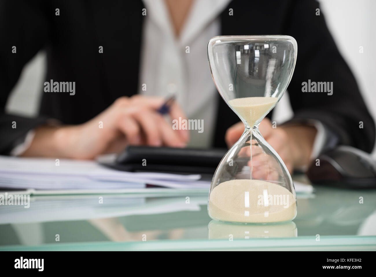 Nahaufnahme der Geschäftsfrau arbeiten im Büro mit der Sanduhr am Schreibtisch Stockfoto