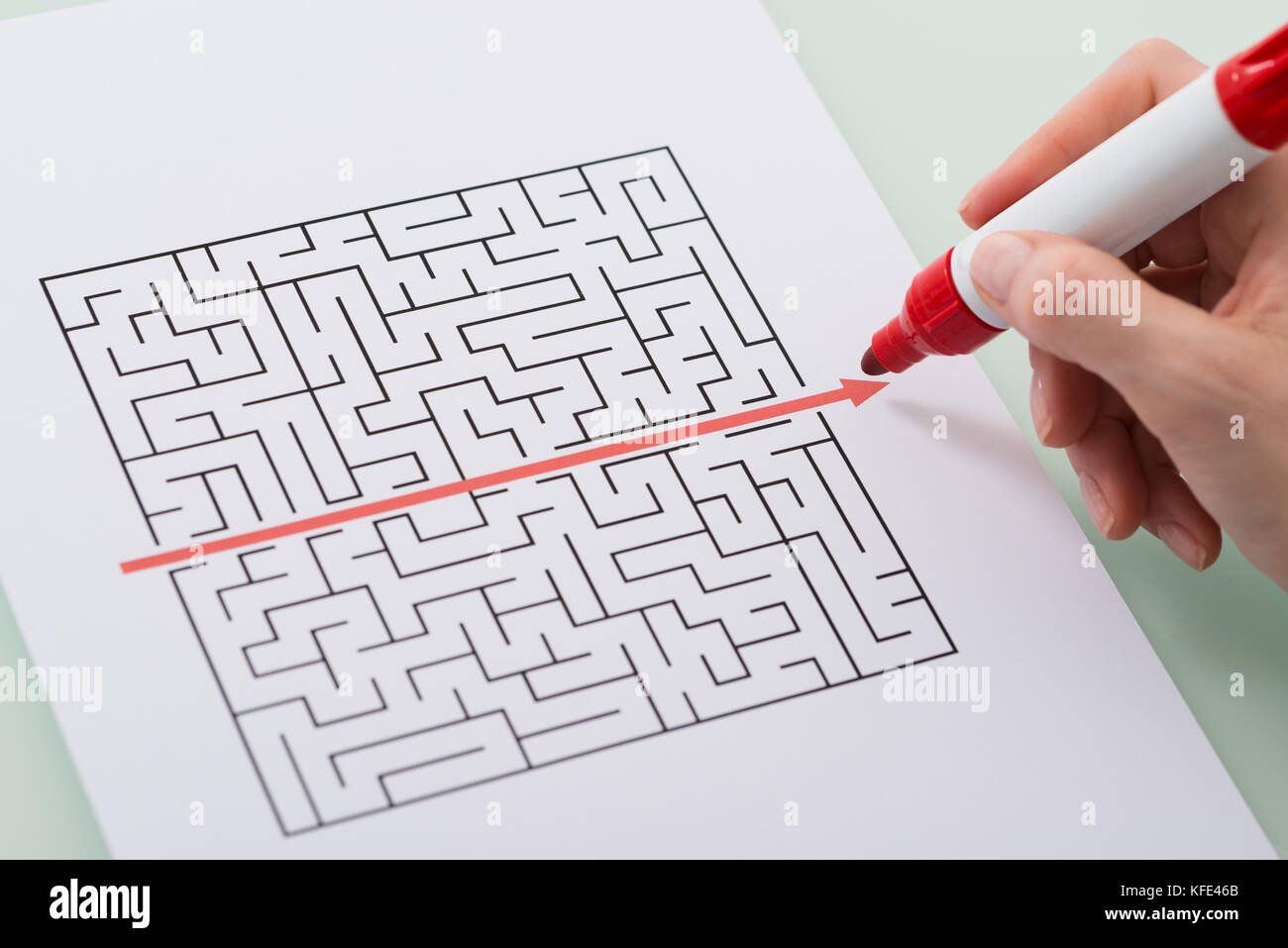 Frau hand Zeichnen von geraden rote Linie über Labyrinth mit roter Markierung Stockfoto