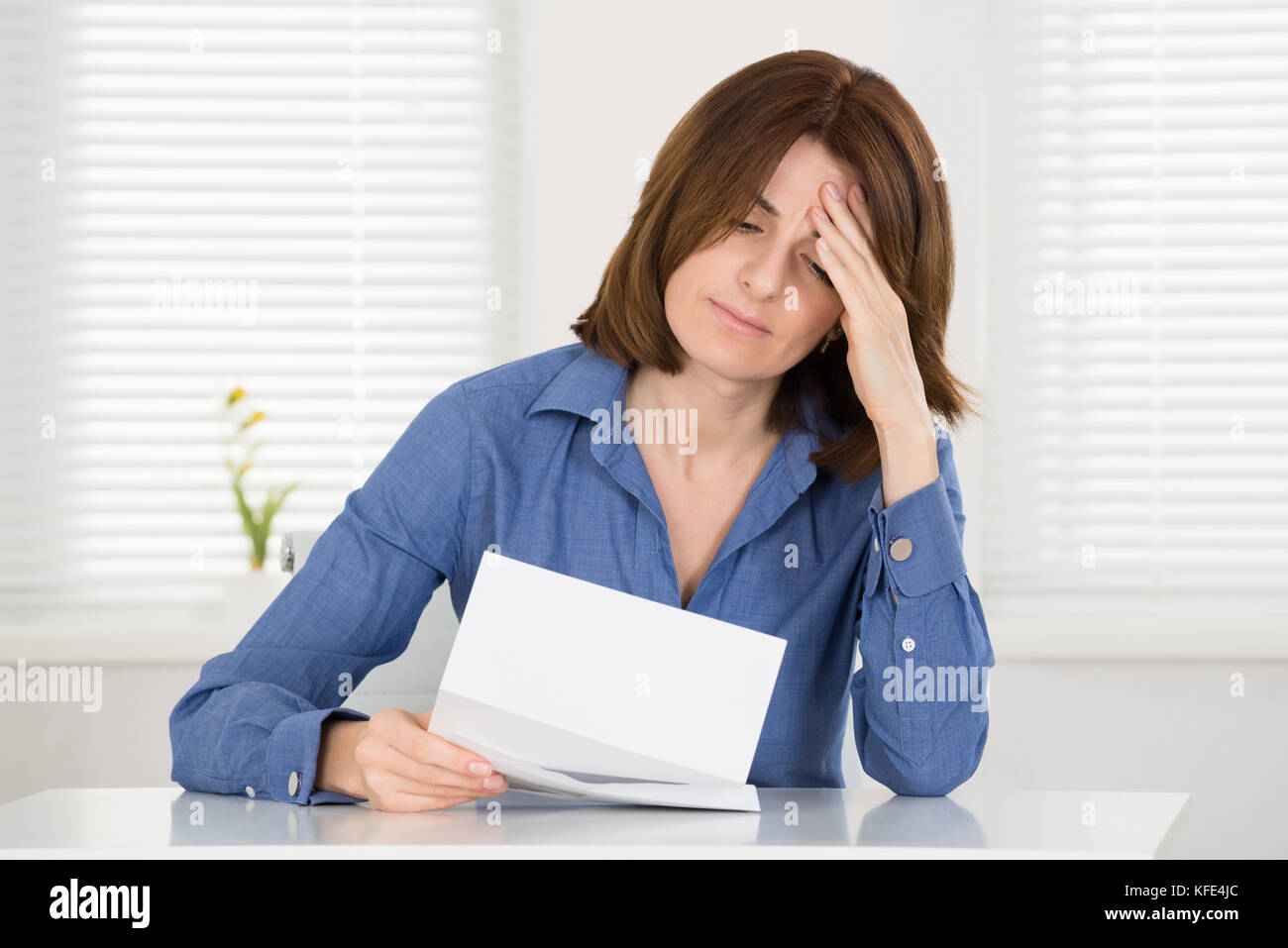 Traurige junge Frau liest Dokument in Office Stockfoto