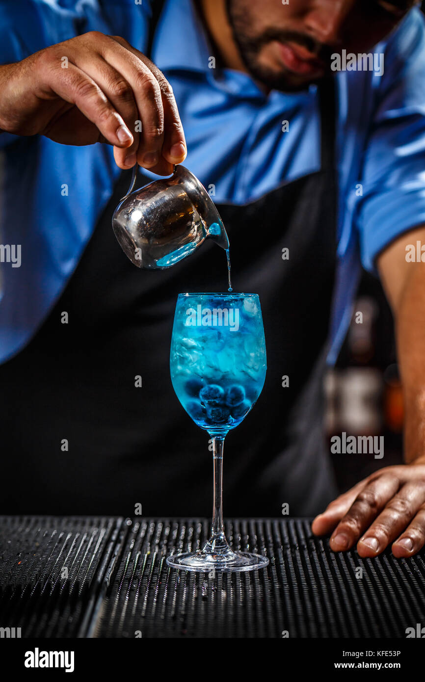 Der Barkeeper ist eine blaue Flüssigkeit in ein Glas, er bereitet die Blaue Lagune cocktail Stockfoto