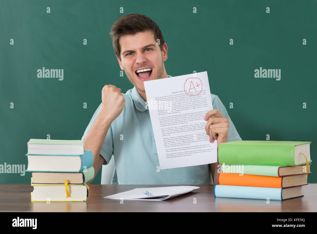 Erfolgreiche Glückliche junge Mann zeigt Prüfungsarbeit Stockfoto