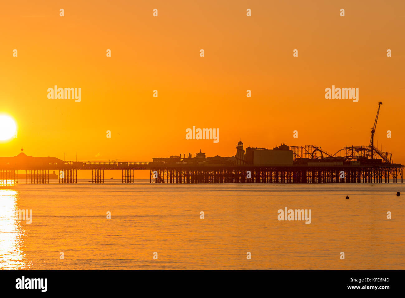 Palace Pier, Brighton im Morgengrauen. die Sonne die Szene in einem sanften orange Glühen gebadet hat Stockfoto