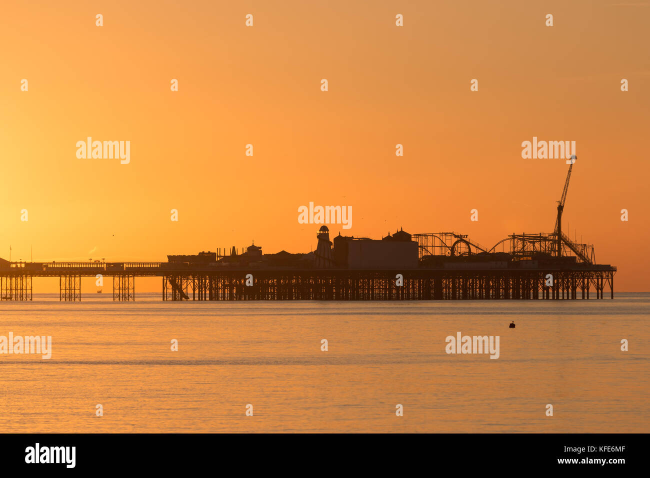 Palace Pier, Brighton im Morgengrauen. die Sonne die Szene in einem sanften orange Glühen gebadet hat Stockfoto