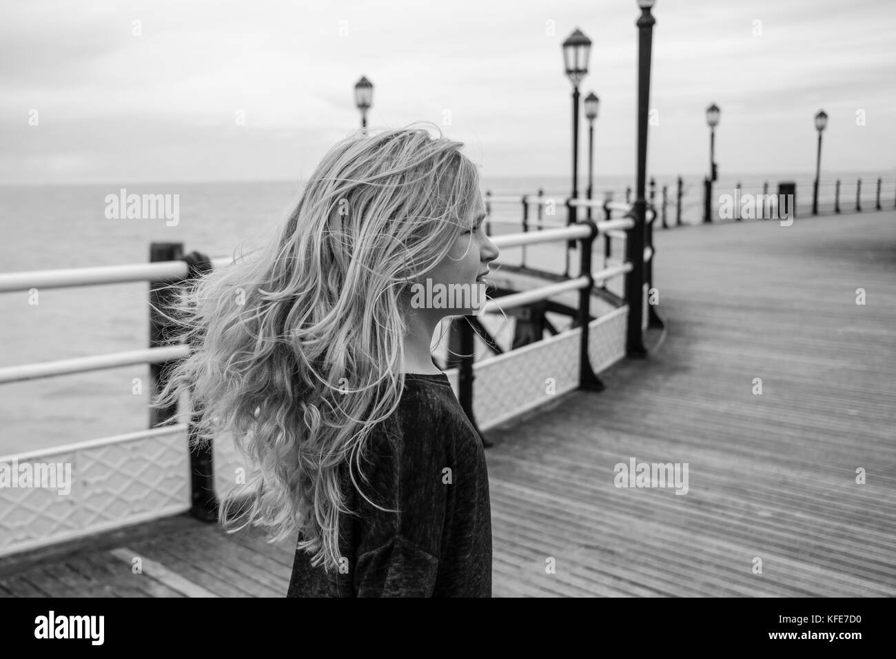 Schöne junge Mädchen mit langen Haaren, schwarzen und weißen Foto an einem windigen Tag im Sommer stehen auf einem Pier Stockfoto