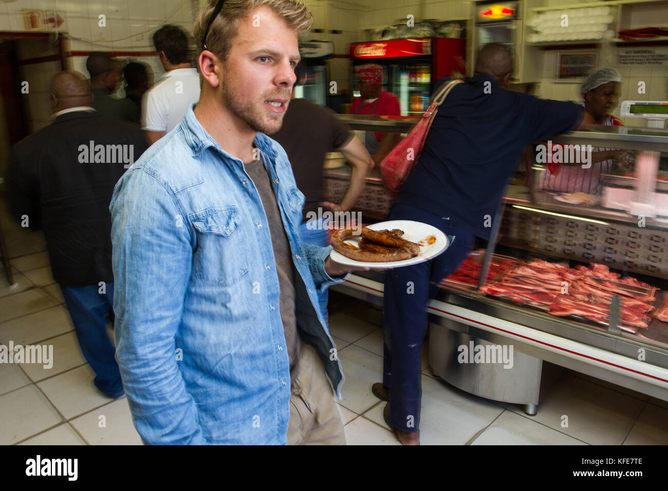 Ein ausländischer Tourist mit einer Platte von Fleisch Mzoli's Township Restaurant in Khayelitsha, Kapstadt, Südafrika Stockfoto