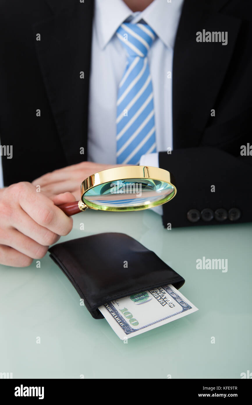 Mittelteil der junge Geschäftsmann Prüfung Geldbörse mit Lupe im Büro Schreibtisch Stockfoto