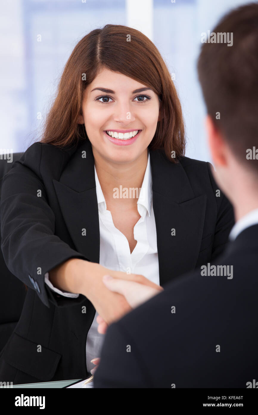 Junge Geschäftsfrau Händeschütteln mit männlichen Partner im Büro Stockfoto