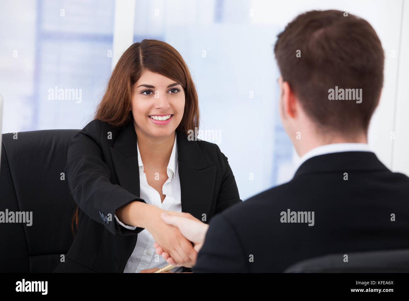 Junge Geschäftsfrau Händeschütteln mit männlichen Partner im Büro Stockfoto