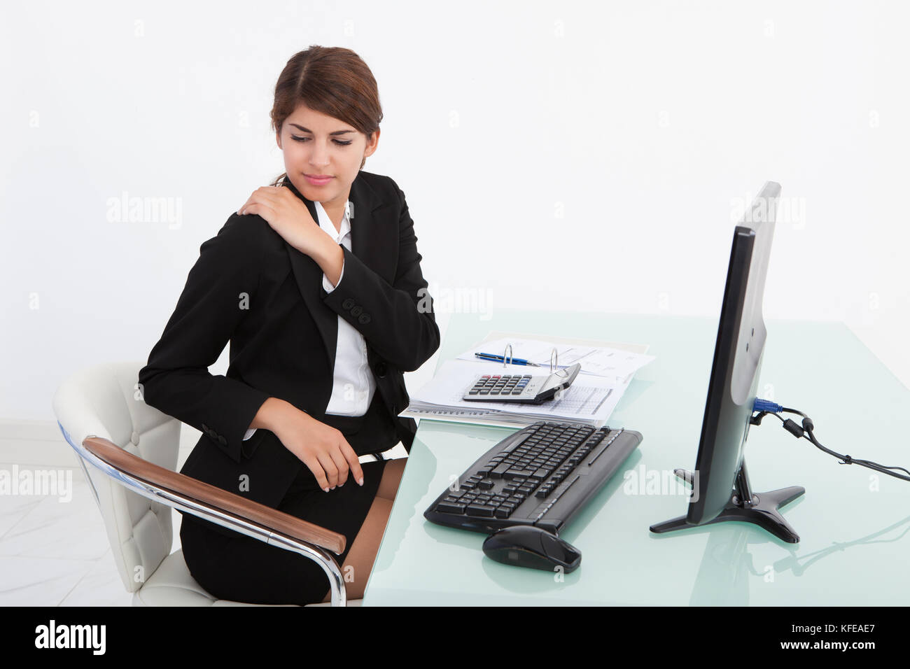 Junge Geschäftsfrau in Schmerzen Schulter, während Computer Schreibtisch im Büro arbeiten Stockfoto