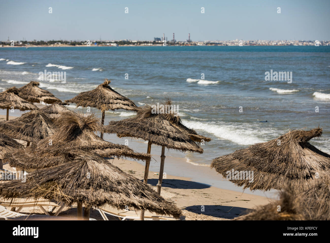 Tunesische Strand mit Sonnenschirmen, blauer Himmel Stockfoto