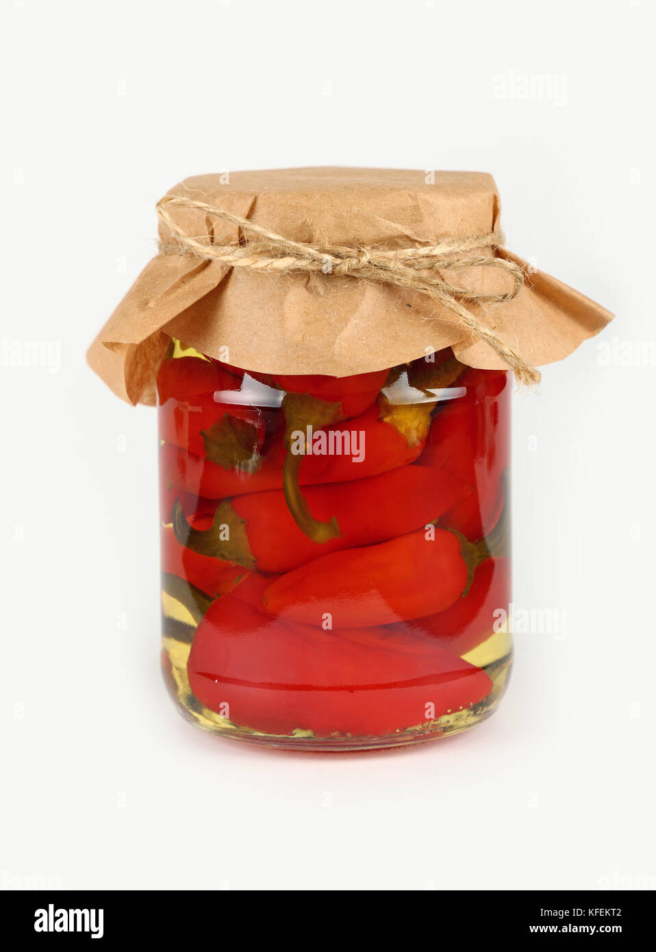 Nahaufnahme von einem Glas Glas eingelegte Cherry Red Hot Chili Peppers pepperoncini mit Kraftpapier Pergament Dekoration und Garn über weißer Hintergrund, Stockfoto