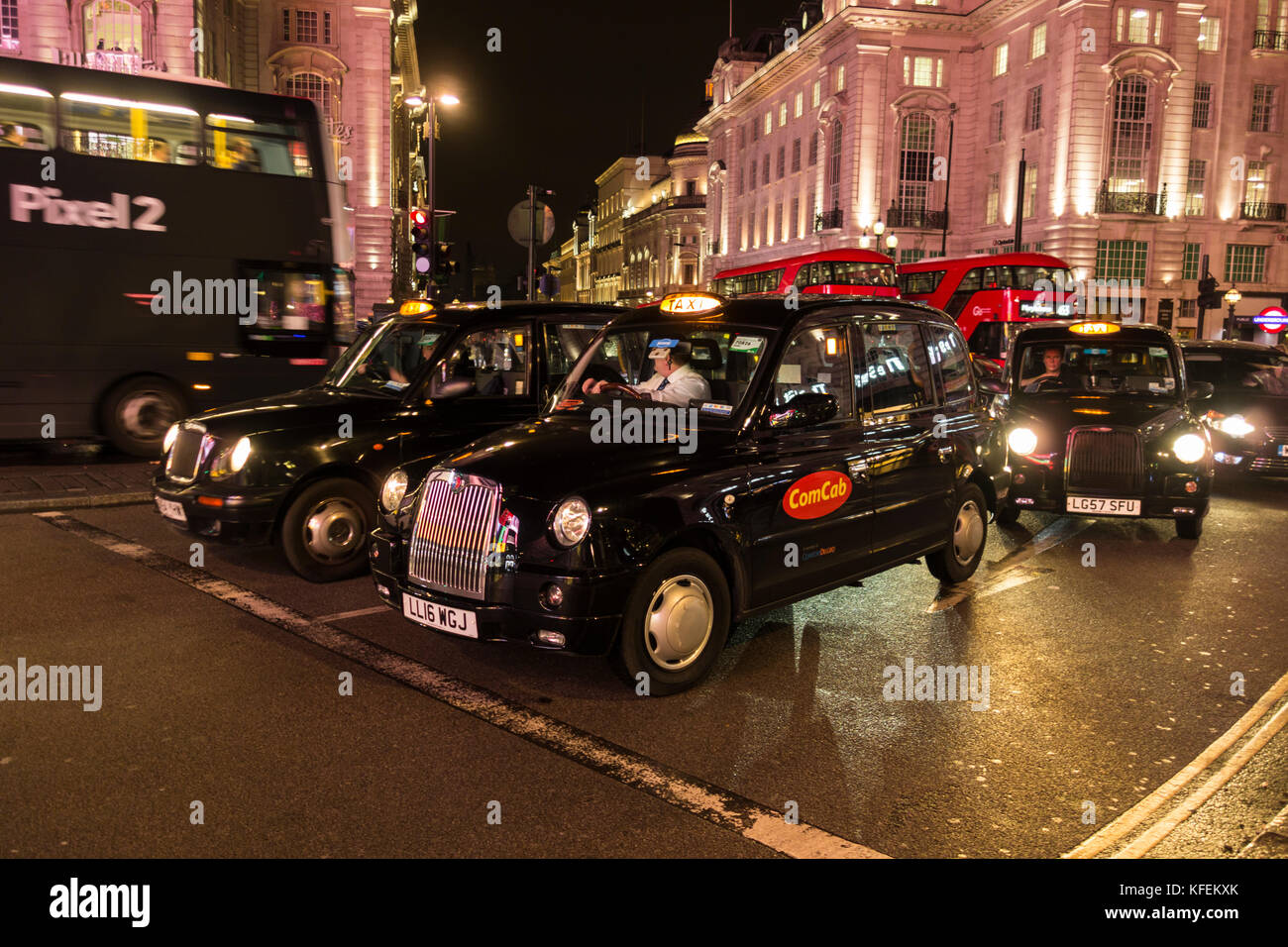 Schwarze Londoner Taxis warten auf die Ampelwechsel an einem überfüllten Piccadilly Circus, London, England, Großbritannien Stockfoto