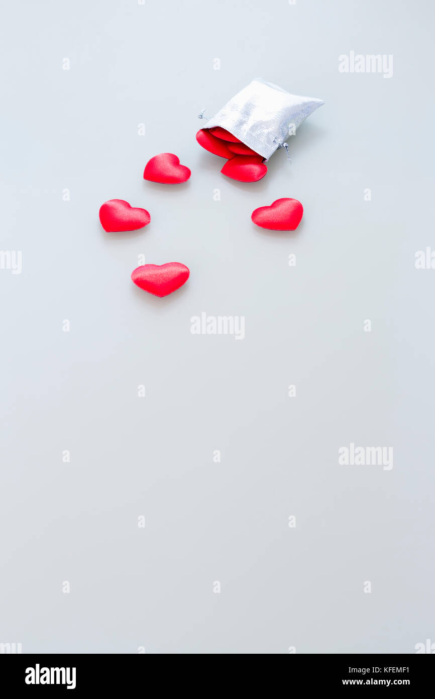 Nahaufnahme eines kleinen Glänzendes Silber Tasche mit niedlichen roten Samt Herzen auf hellgrauem Hintergrund gefüllt. Konzept der romantischen Liebe Geschenk für Paare, valenti Stockfoto