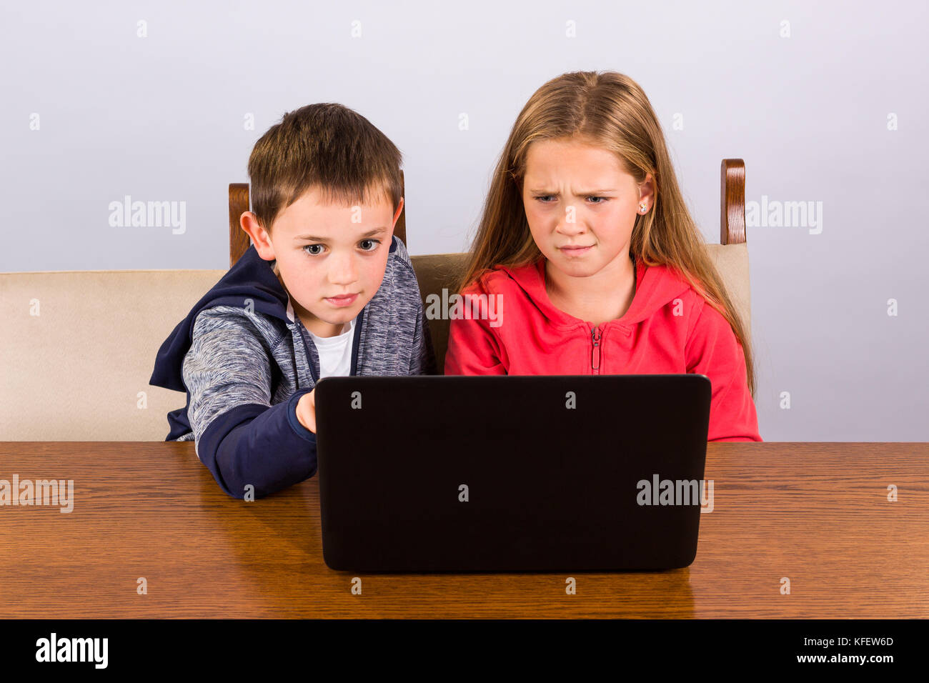 Junge zeigt etwas Seltsames an seine Schwester auf einem Laptop Stockfoto