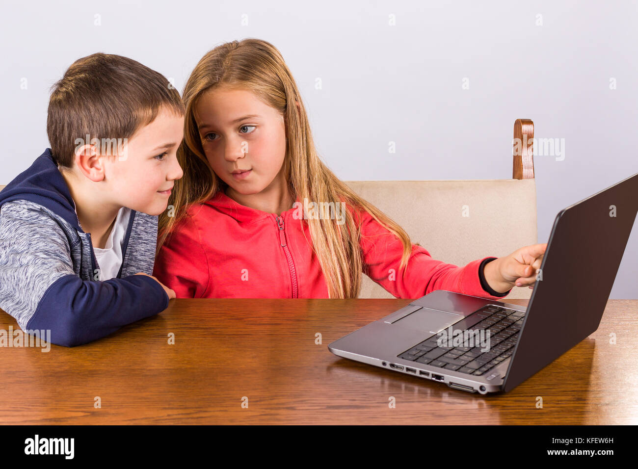 Junge Mädchen zeigt, etwas zu ihrem Bruder auf einem Laptop Stockfoto