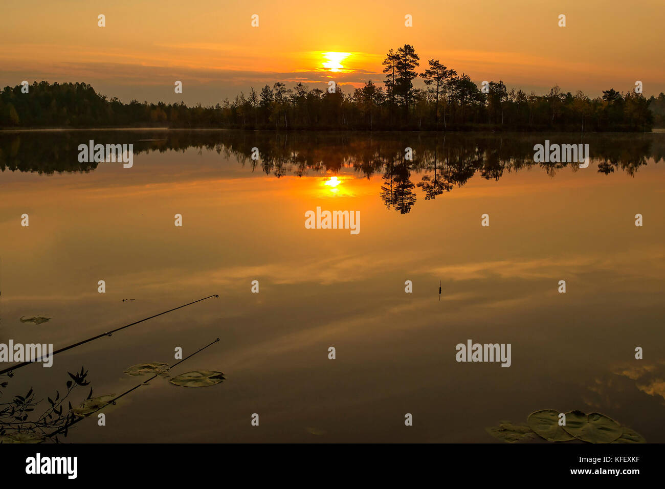 Sonnenuntergang auf dem See mit der Reflexion der Sonne im Wasser. Rod und Schwimmstellung. Angeln auf dem See Stockfoto