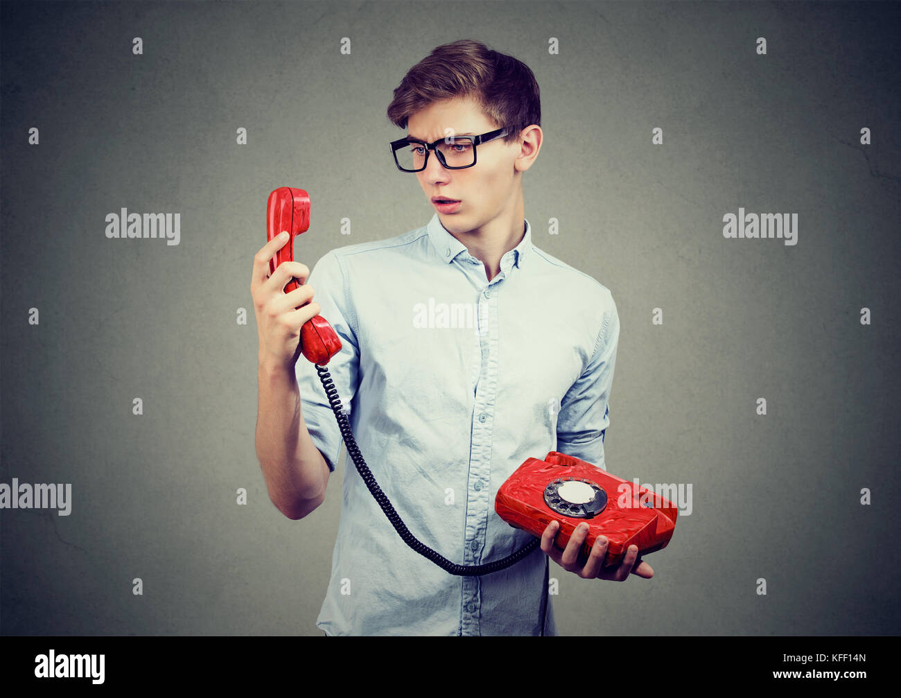 Verwirrt teenager Mann an altmodische Telefon suchen Stockfoto