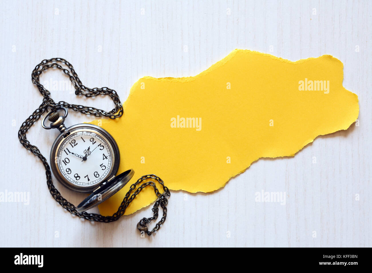 Stück leere gelbe Papier für Text in der Nähe von taschenuhr auf weißem Holz- Hintergrund Stockfoto