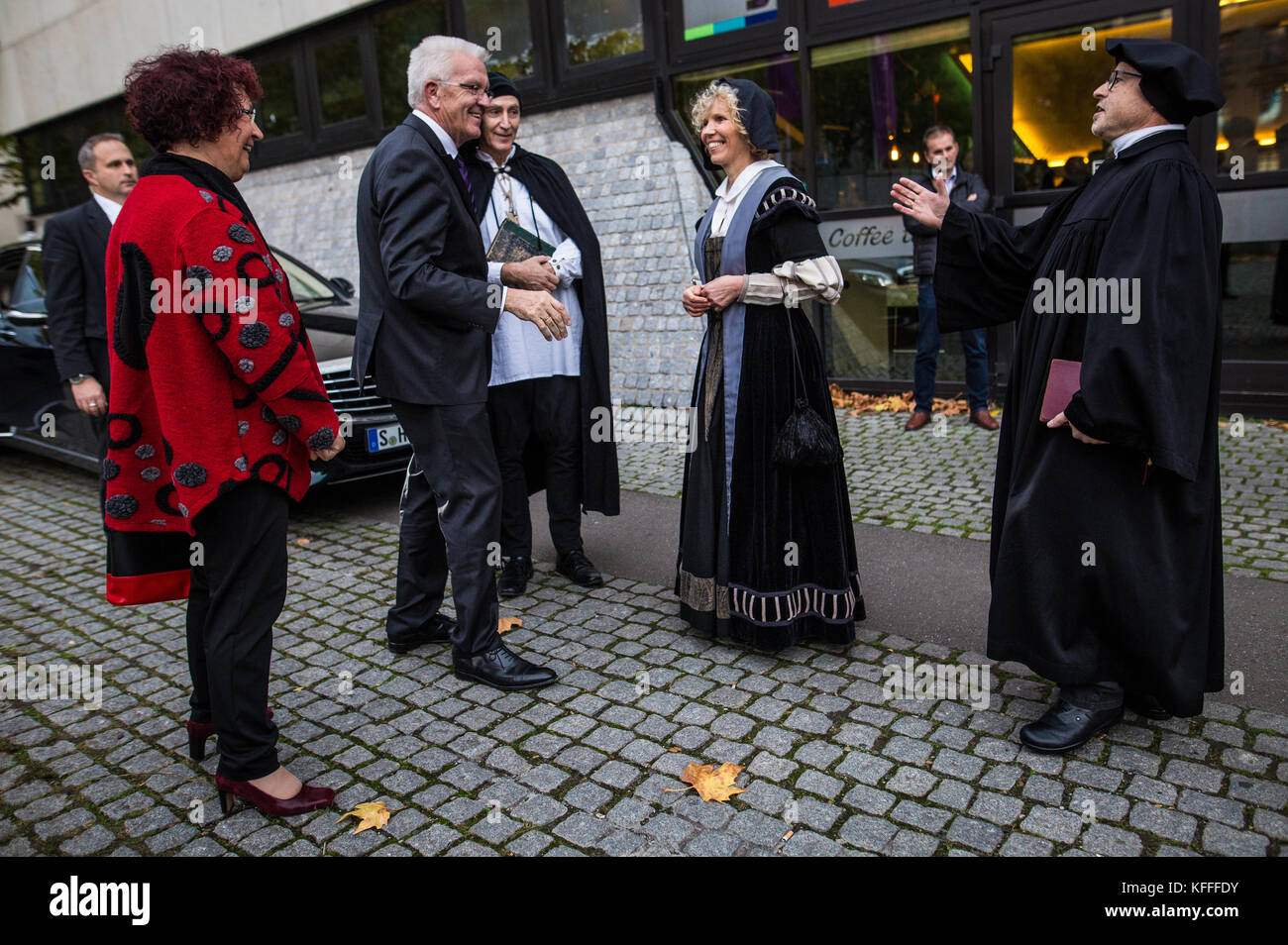 Winfried Kretschmann (2.f.l., Buendnis 90/die Gruenen), Premierminister von Baden-Württemberg, und seine Frau Gerlinde (l.) werden vor dem Museum Weltkulturen in Mannheim am 28. Oktober 2017 von einem als Martin Luther gekleideten Mann begrüßt. Foto: Christoph Schmidt/dpa Stockfoto