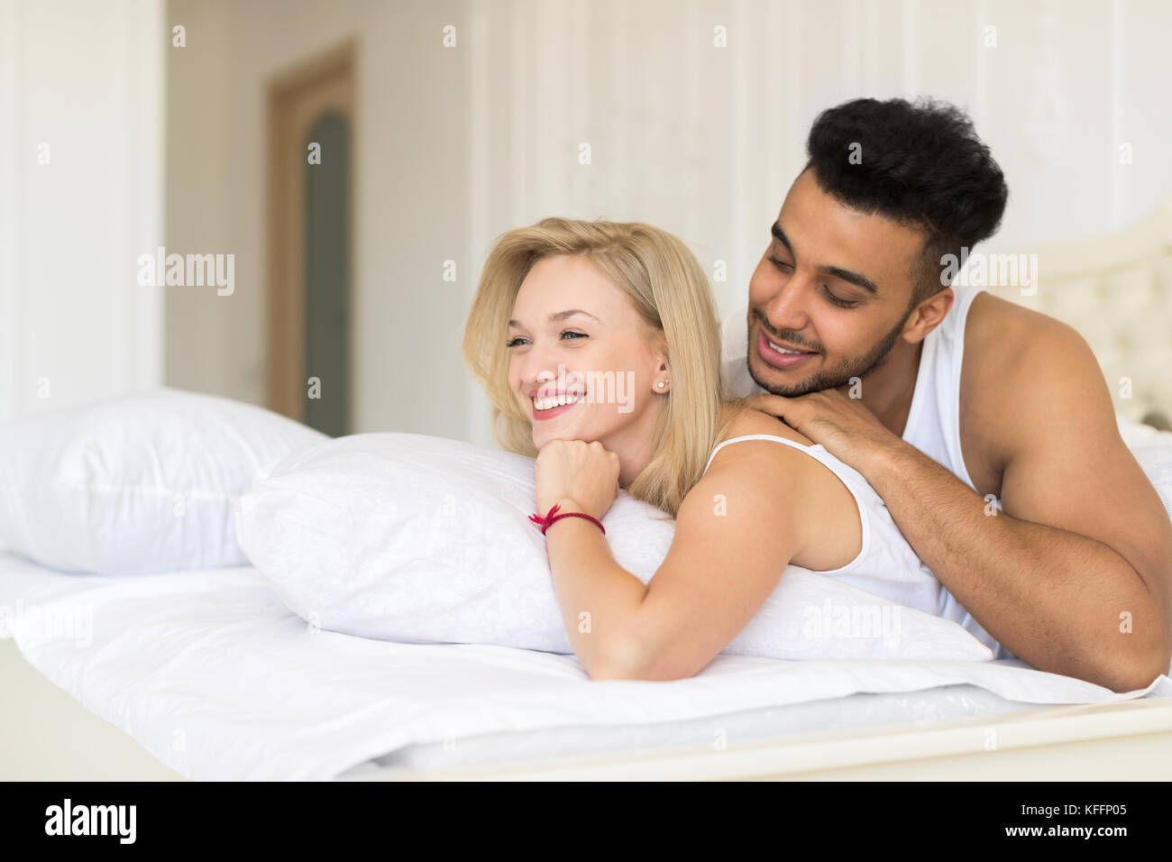 Junges Paar im Bett liegt, glückliches Lächeln Hispanic Mann und Frau Stockfoto