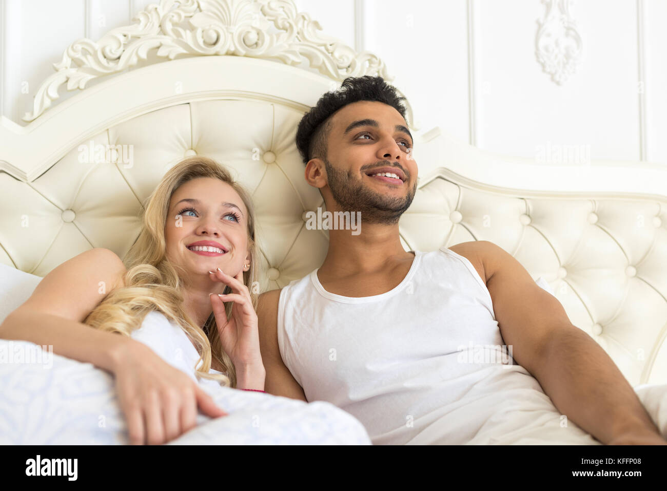 Junges Paar im Bett liegt, glückliches Lächeln Hispanic Mann und Frau die Suche nach Speicherplatz zu kopieren. Stockfoto