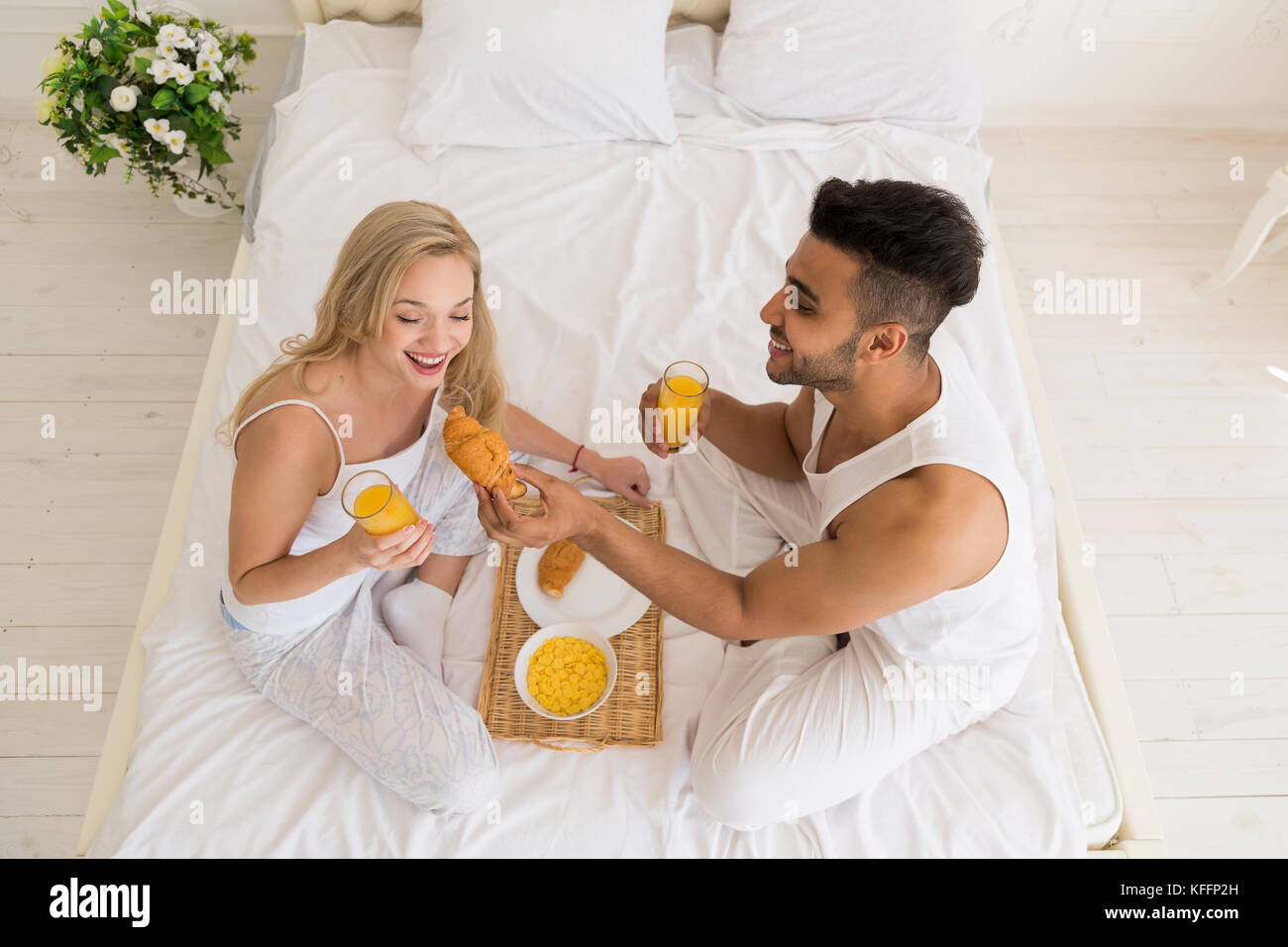 Junges Paar Frühstück im Bett sitzend, glückliches Lächeln Hispanic Mann und Frau morgen top Winkel anzeigen Stockfoto