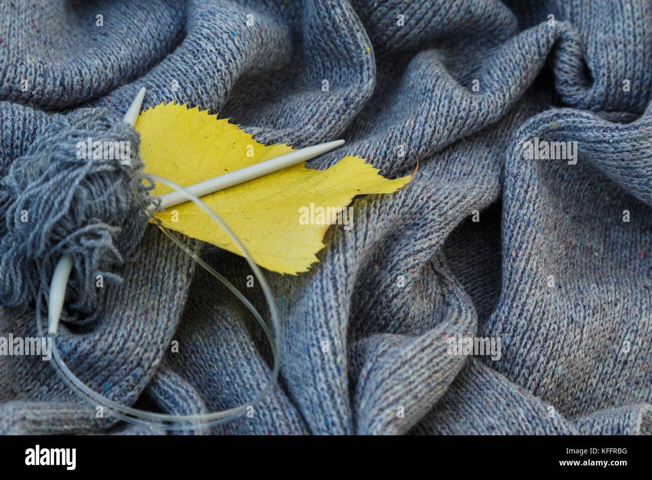 Hintergrund der gestrickt grau Bettwäsche von Ziegenmilch Wolle mit Stricknadeln oder auf eine Strickmaschine in Wellen mit Metall Stricknadeln gelegt, gelb Stockfoto