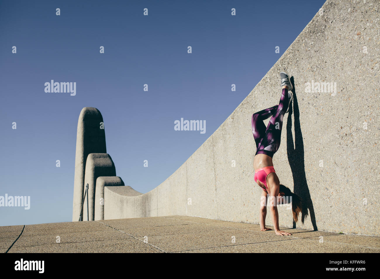 Körperlich fit Frau tun Hand stand im Freien. Gesunde weibliche stehen auf Händen und Füßen gegen eine Wand. Stockfoto