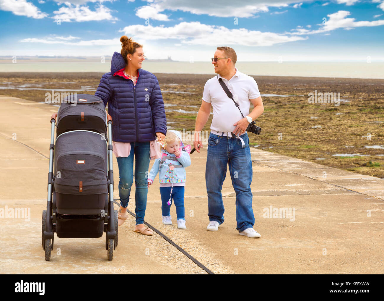 Junge Familie zu Fuß entlang der Promenade am Meer Stockfoto