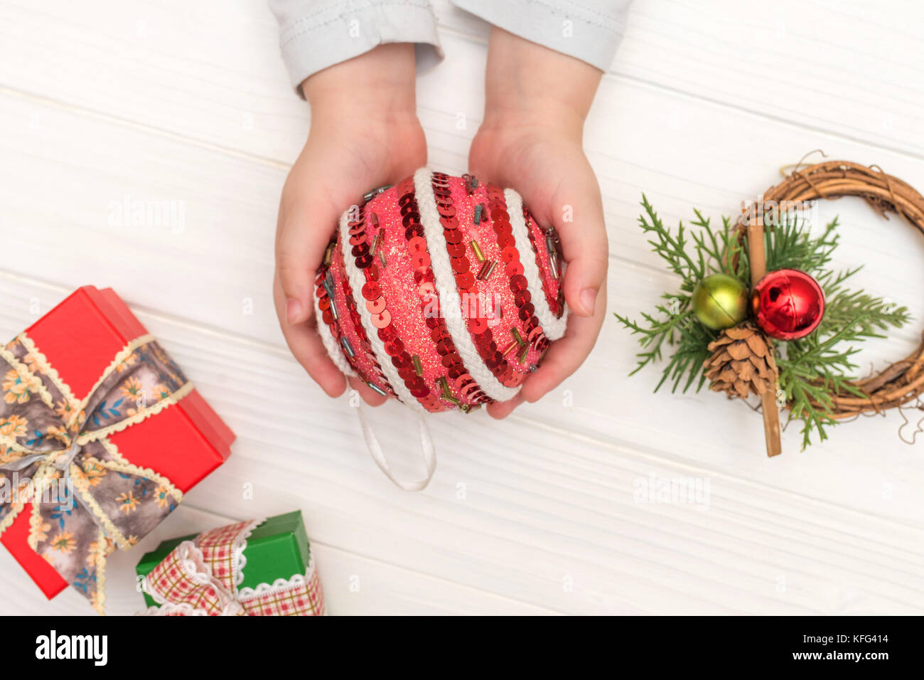 Weihnachten Kalender auf weißem Hintergrund. Child's Hände, die Christmas Ball in der Nähe von geschenkboxen auf weißen Tisch Stockfoto