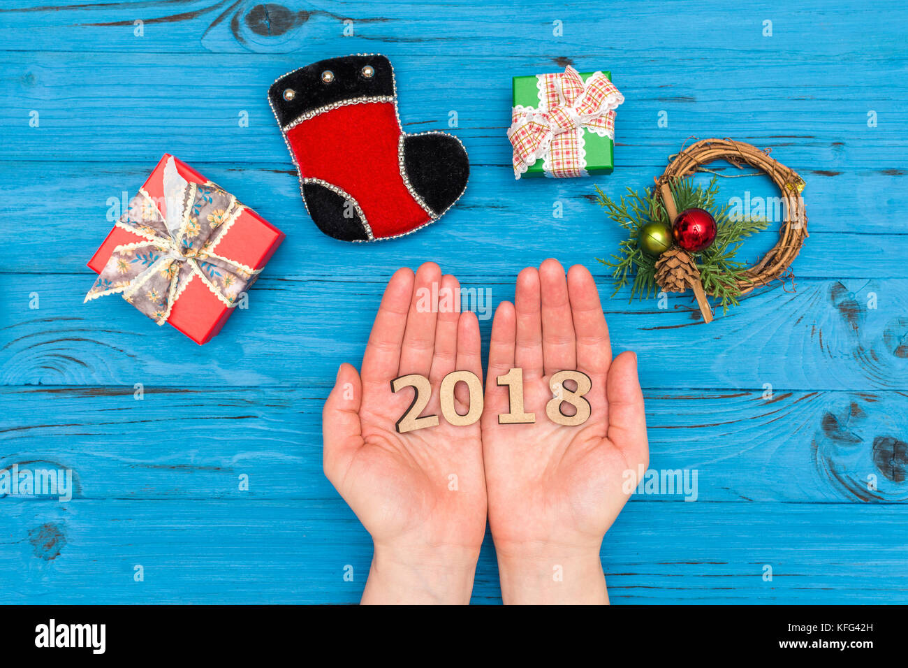 Woman's Hände, die Zahl 2018 in der Nähe von geschenkboxen und Neues Jahr Ornamente auf Blau alte Tabelle Stockfoto