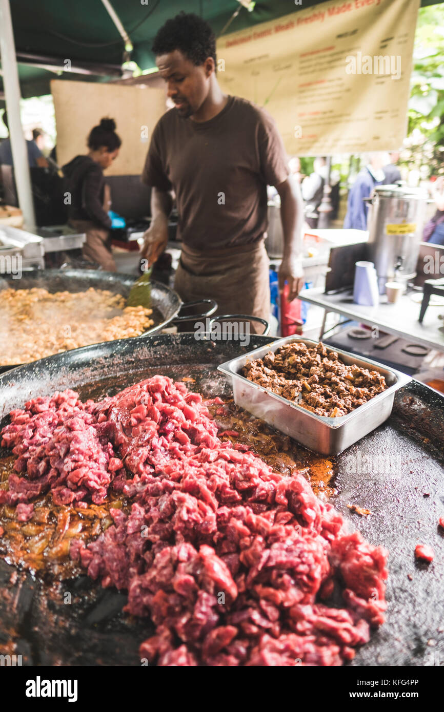Ein Mann kocht Fleisch auf einem riesigen Grill im Borough Markets, London, England Stockfoto