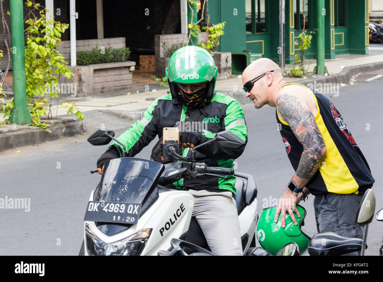 Mann mit einem Fahrrad Taxi schnappen, das scheint ein off duty Polizist in Kuta, Bali, Indonesiaride sharing zu werden. Stockfoto