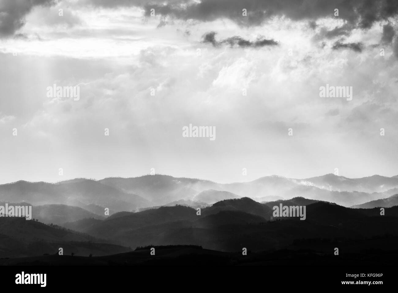 Die verschiedenen Schichten der Hügel und Berge mit Nebel zwischen Ihnen, mit Sonnenstrahlen, die durch die Wolken Stockfoto