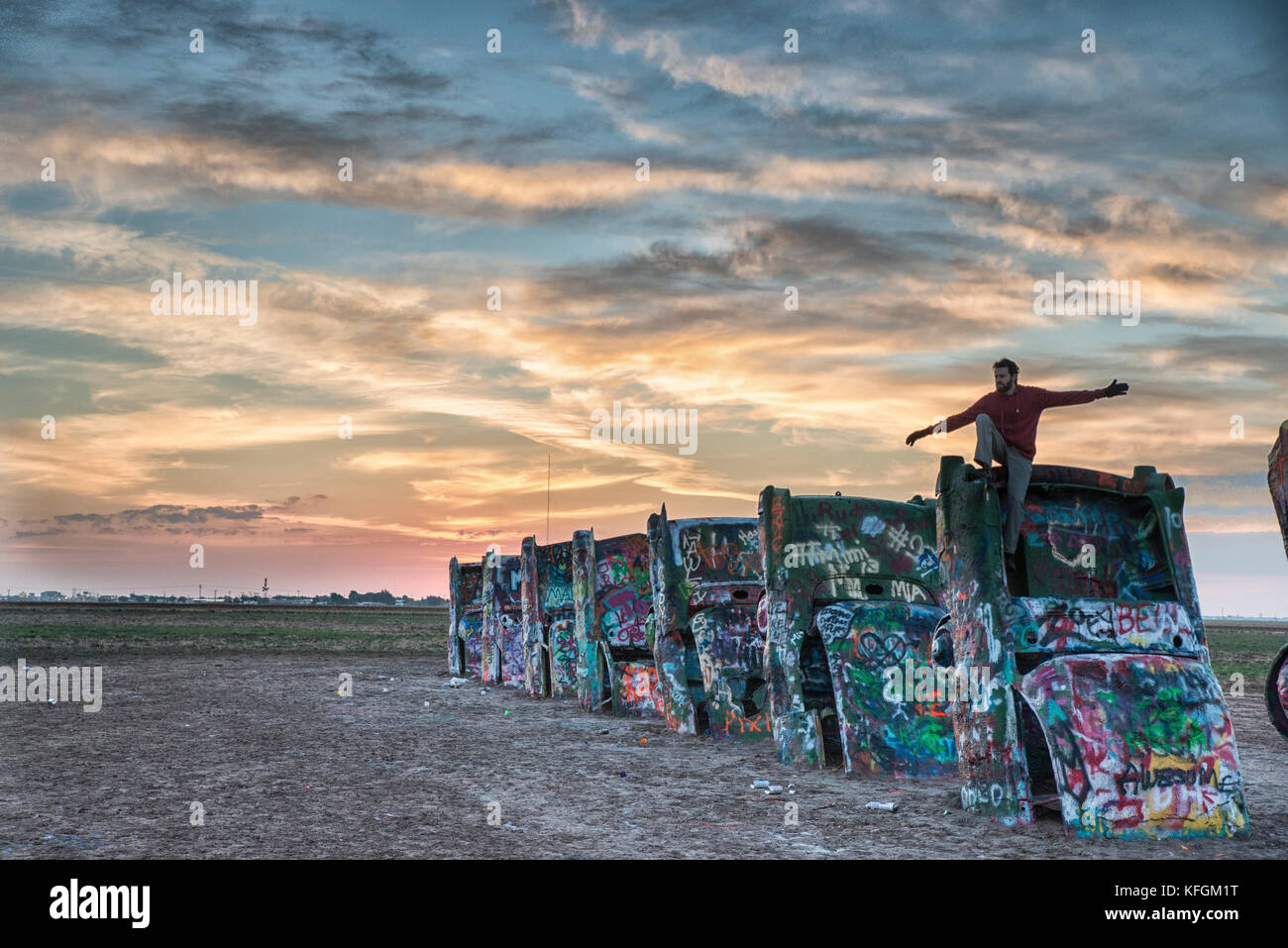 Amarillo, Texas, USA. Oktober 2015. Mann sitzt auf einem cadillac mit offenen Armen auf der Cadillac Ranch während Sonnenaufgang. Stockfoto