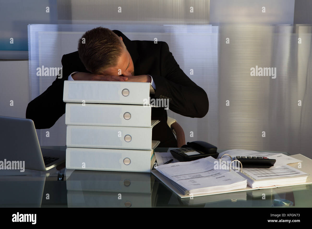 Erschöpft schlafen ein Geschäftsmann eine der Dateien stack wie er spät im Büro während des Abends arbeitet, wie er versucht, eine Frist für die Morgen zu begegnen Stockfoto
